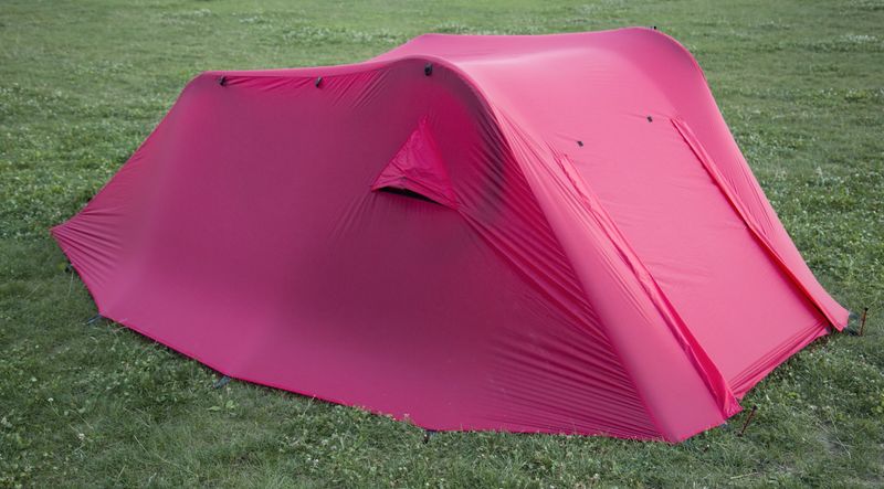 Tike bike tent prototype with a pink fly pitched on two mountain bikes on a meadow